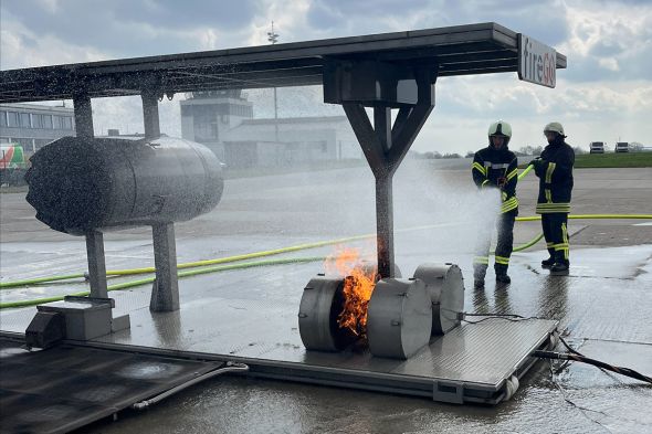 Zwei Feuerwehrleute spritzen Wasser auf eine brennendes Fahrwerk