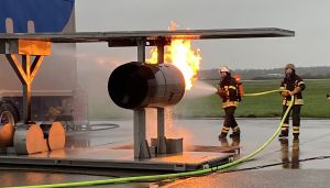 Two firefighters spray water on a burning turbine