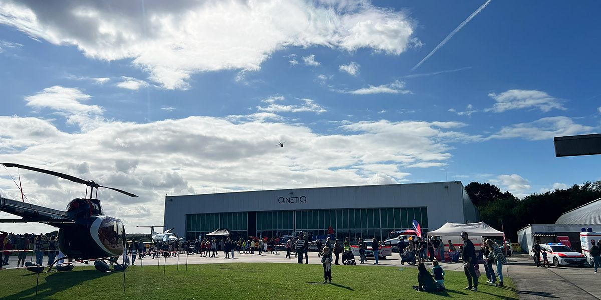 Helikopter und Menschen vor Hangar