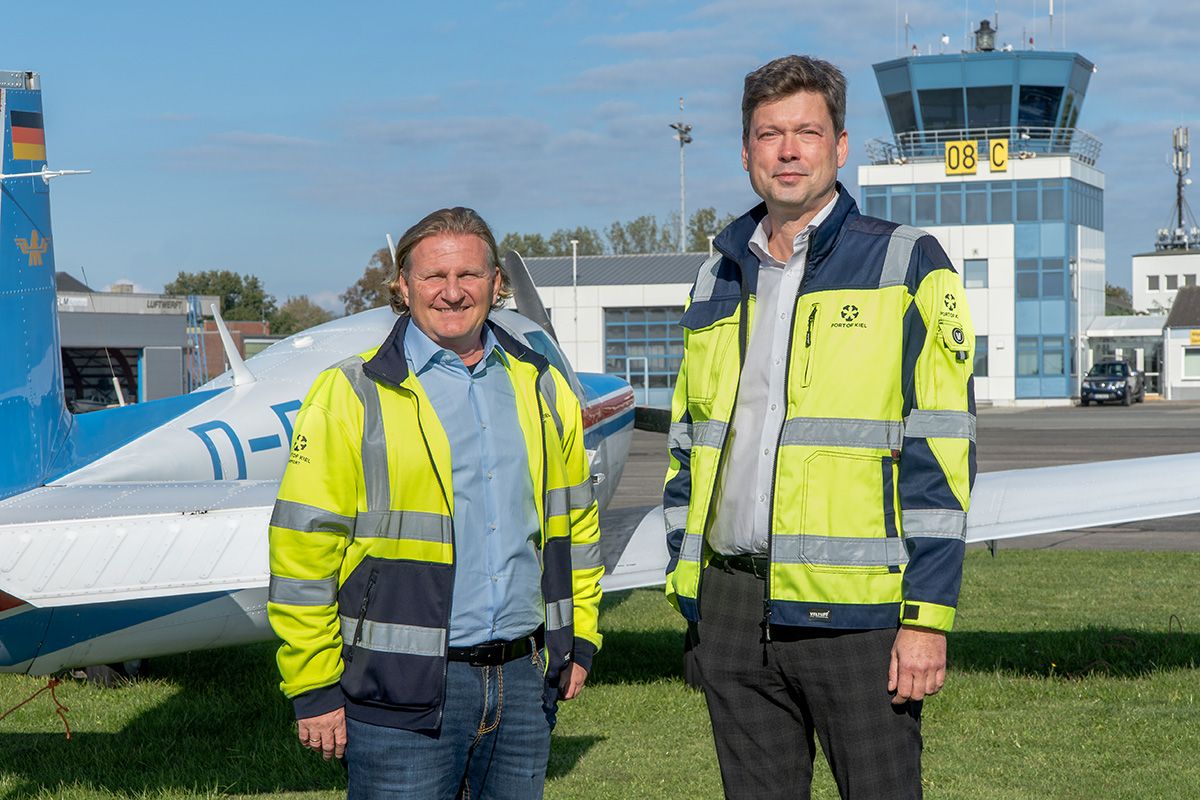 Marcus Breuer und André Bender vor Flughafenkulisse