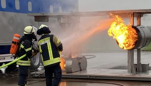 Two firefighters spray water on a burning turbine