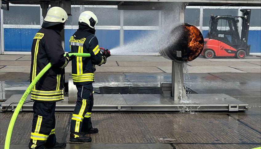 Two firefighters spray water on a burning turbine