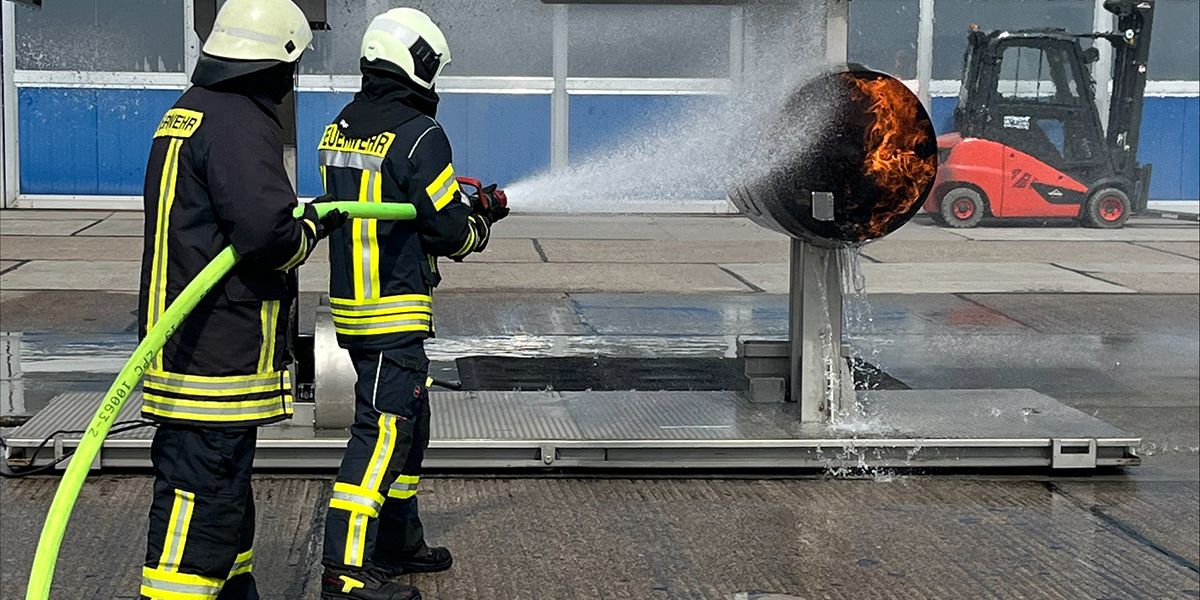Zwei Feuerwehrleute spritzen Wasser auf eine brennende Turbine